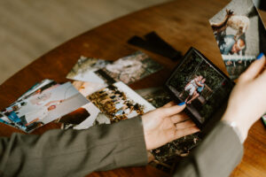 Een tafel vol foto's die in de Wissel Frame voor Liggende Foto's fotolijst worden gestopt door een hand met nagellak