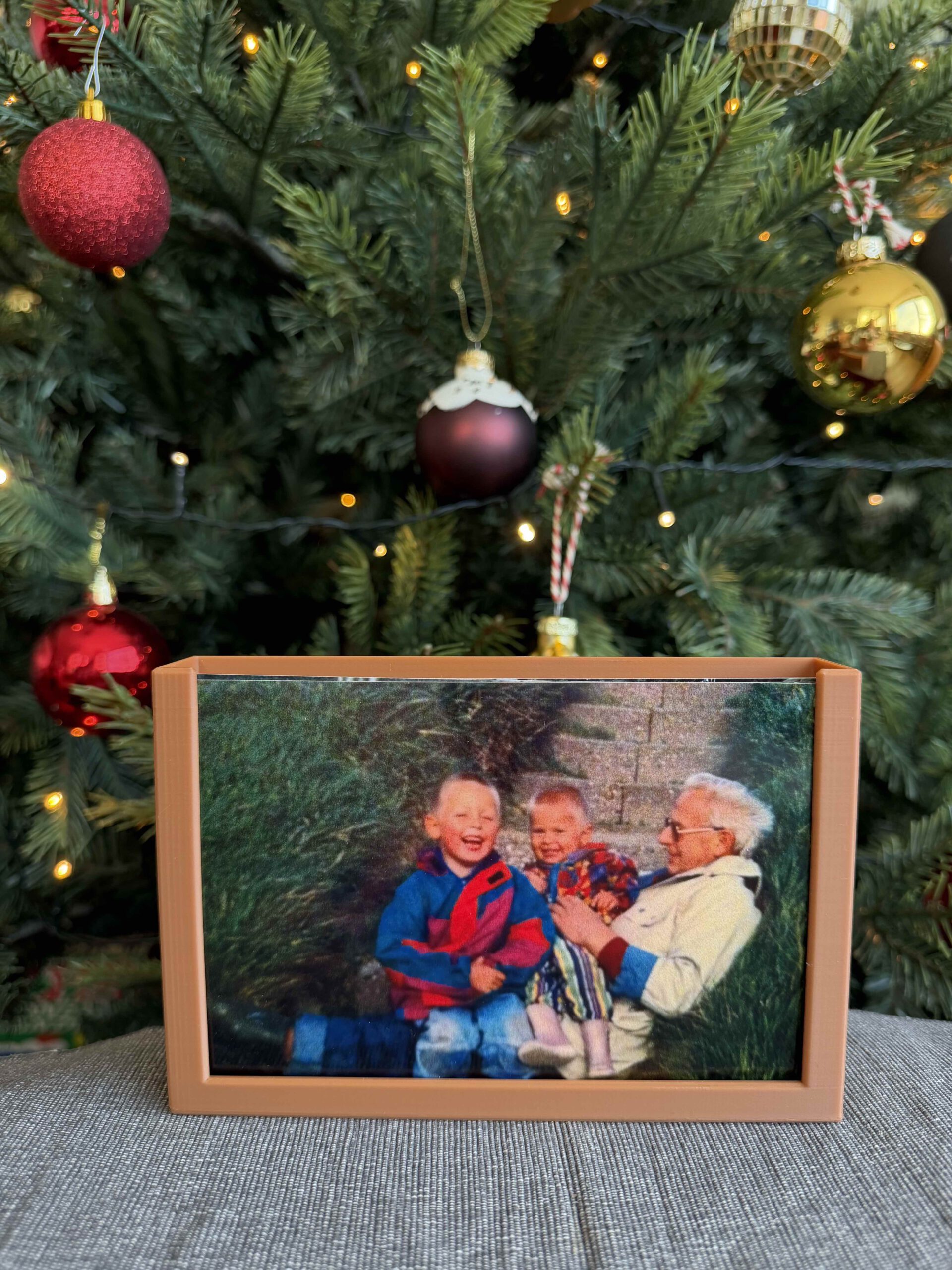 Kerstfoto van opa en kleinkinderen bij de kerstboom